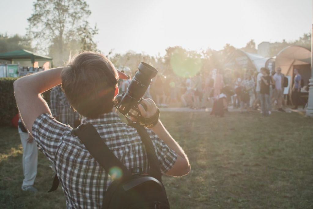 man-in-grey-and-white-plaid-shirt-with-backpack-and-dslr-camera-on-hand-mx1y4azf6tm